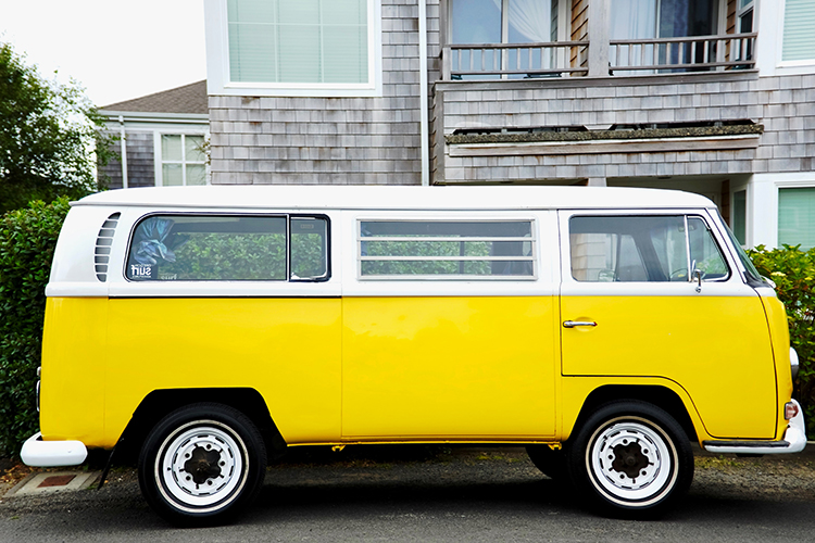 A bright yellow V W van parked on the street.