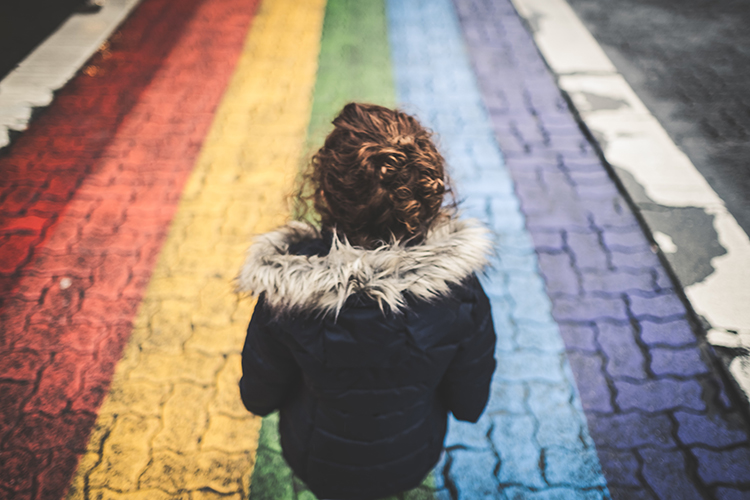 Child sitting on a rainbow-colored brick road.